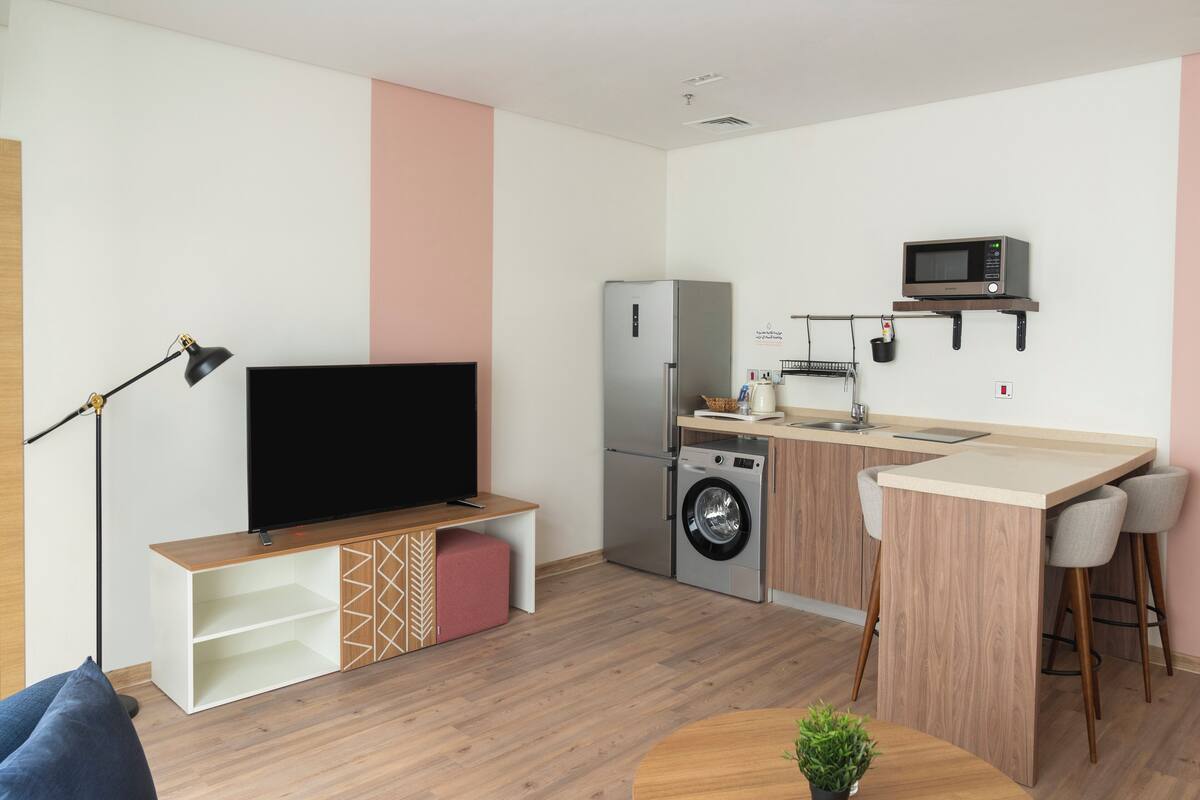 A modern kitchen with a built-in washing machine, a microwave, and a small bar area.
