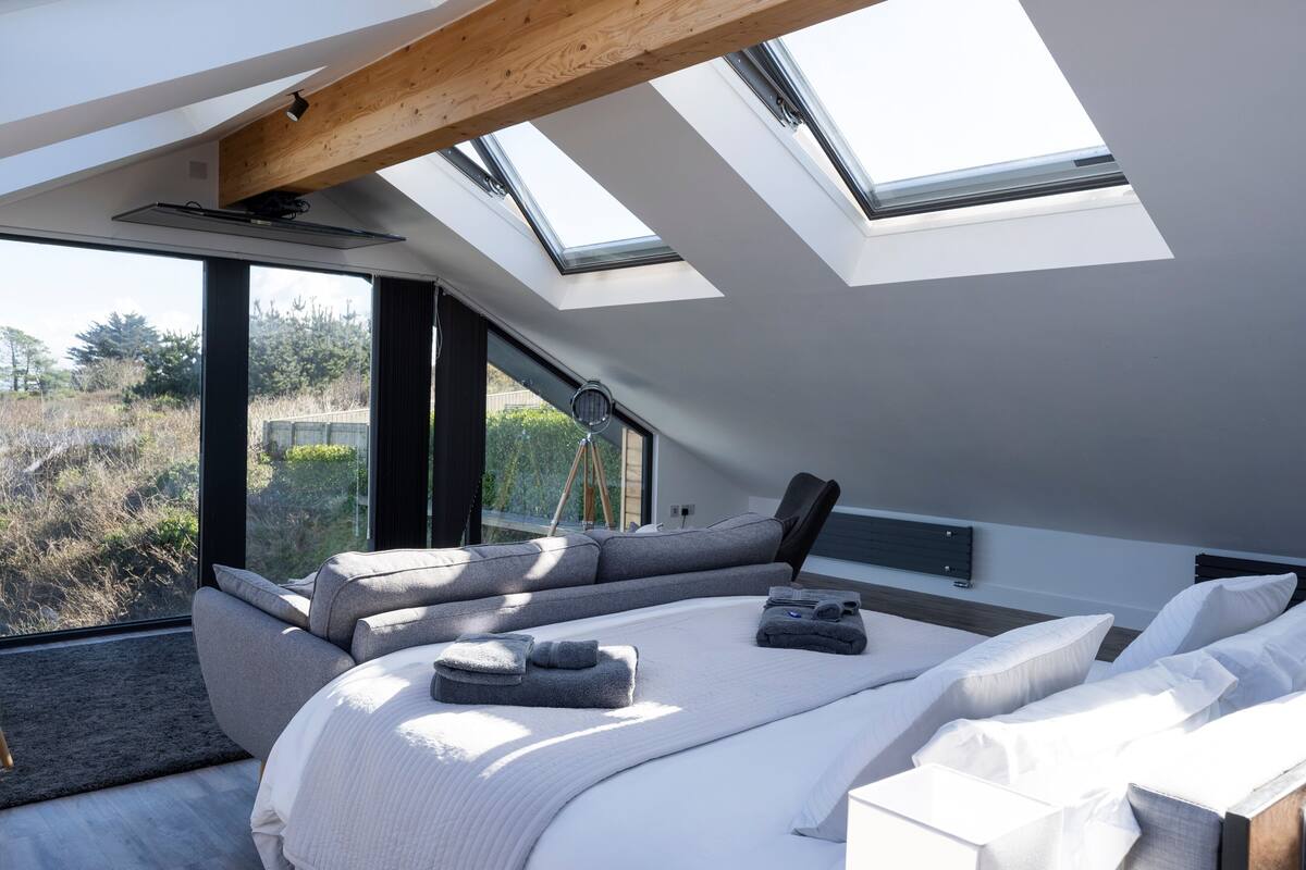 A modern bedroom with skylights, a large bed, and a view of the outdoors.