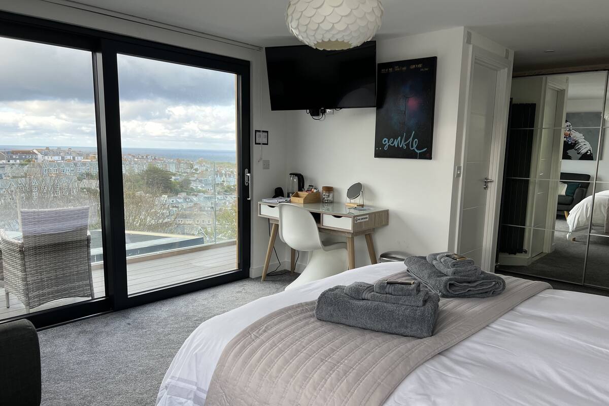 A modern hotel room with a large bed, a desk, and a view of the city.