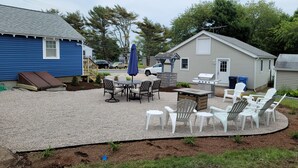 Ein Garten mit Grillplatz, Sitzgelegenheiten im Freien und einem Geräteschuppen.