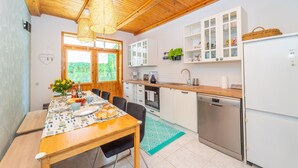 Et moderne køkken med træloft, hvide skabe og et spiseområde med et bord dækket til fire personer.