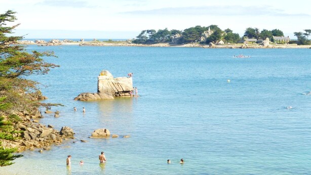 A coastal scene with clear water, rocky outcrops, and a few people swimming. - Cottage in Plougasnou near Stunning Beaches (Plougasnou)