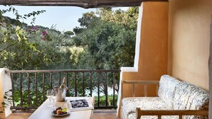 Ein Balkon mit einem Holztisch, einer gepolsterten Bank und einer Champagnerflasche.