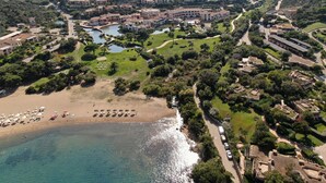 Ein Luftbild eines Küstenresorts mit Strand, Villen und einem kleinen See.