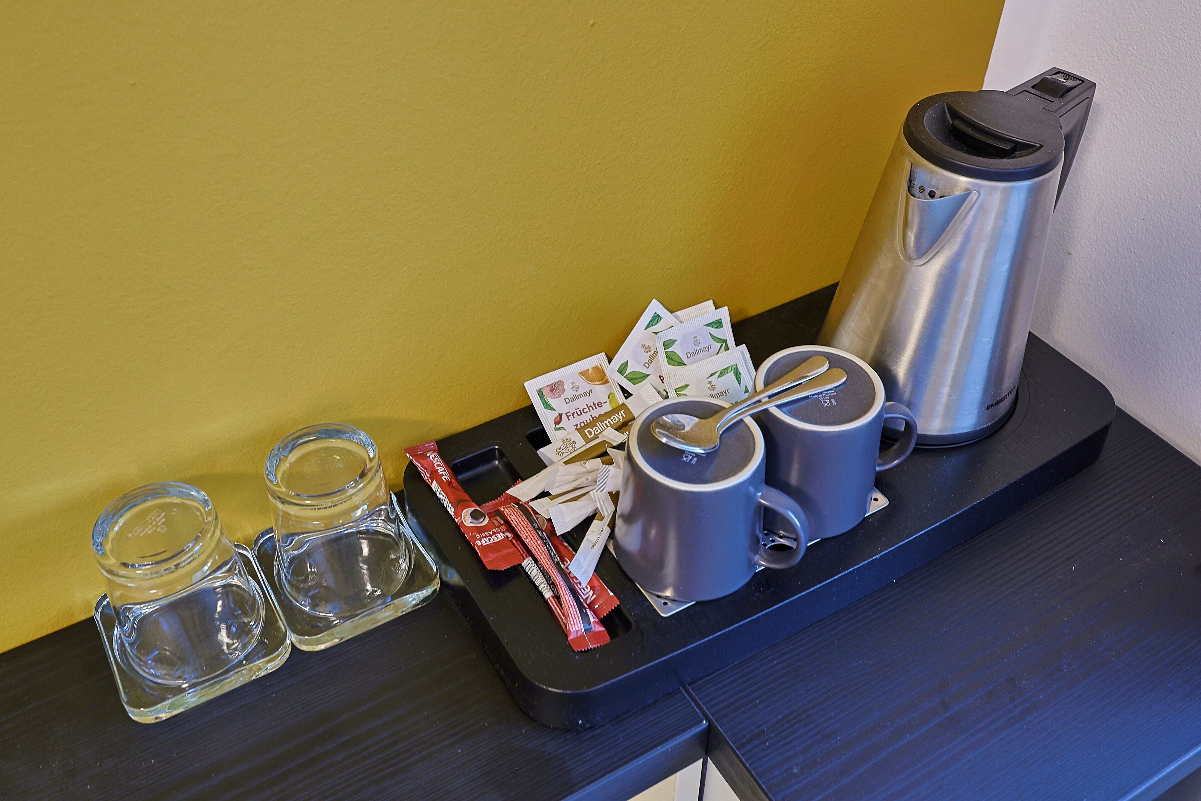 A tray with a coffee maker, two mugs, salt and pepper shakers, a packet of sugar, and some receipts.