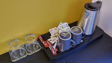 A tray with a coffee maker, two mugs, salt and pepper shakers, a packet of sugar, and some receipts.
