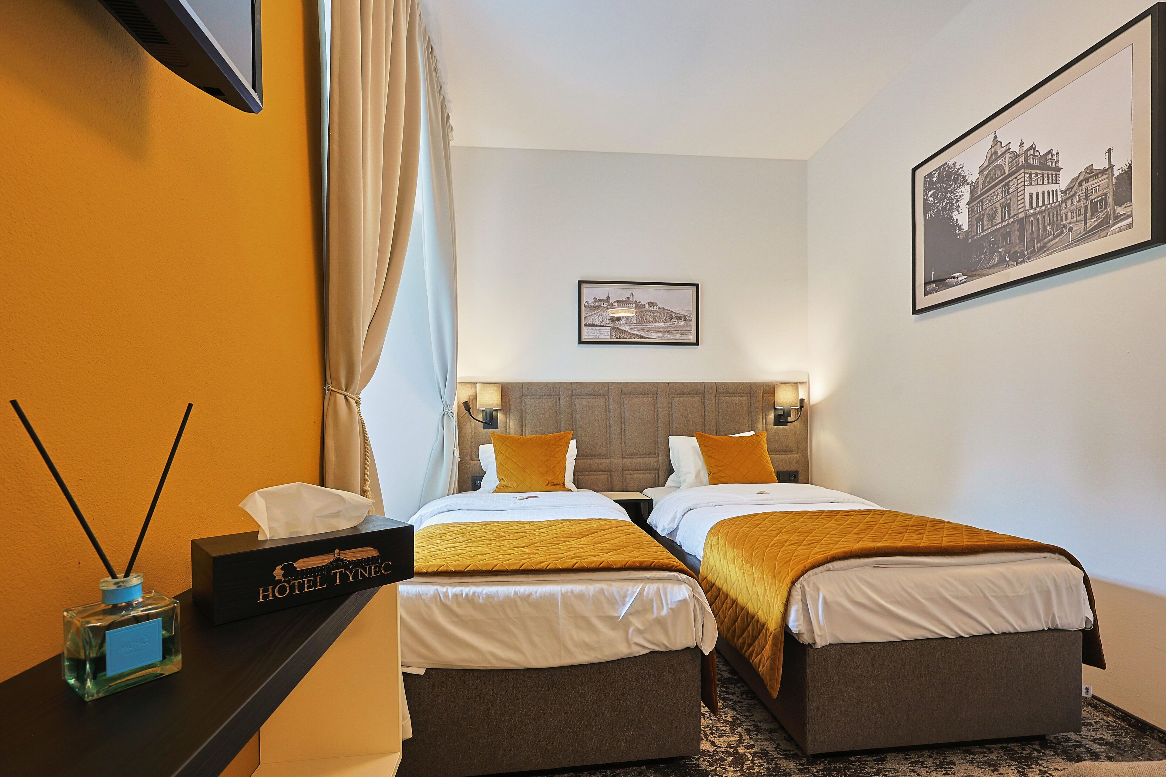 Habitación de hotel con dos camas, un minibar, un escritorio y un cuadro en la pared.