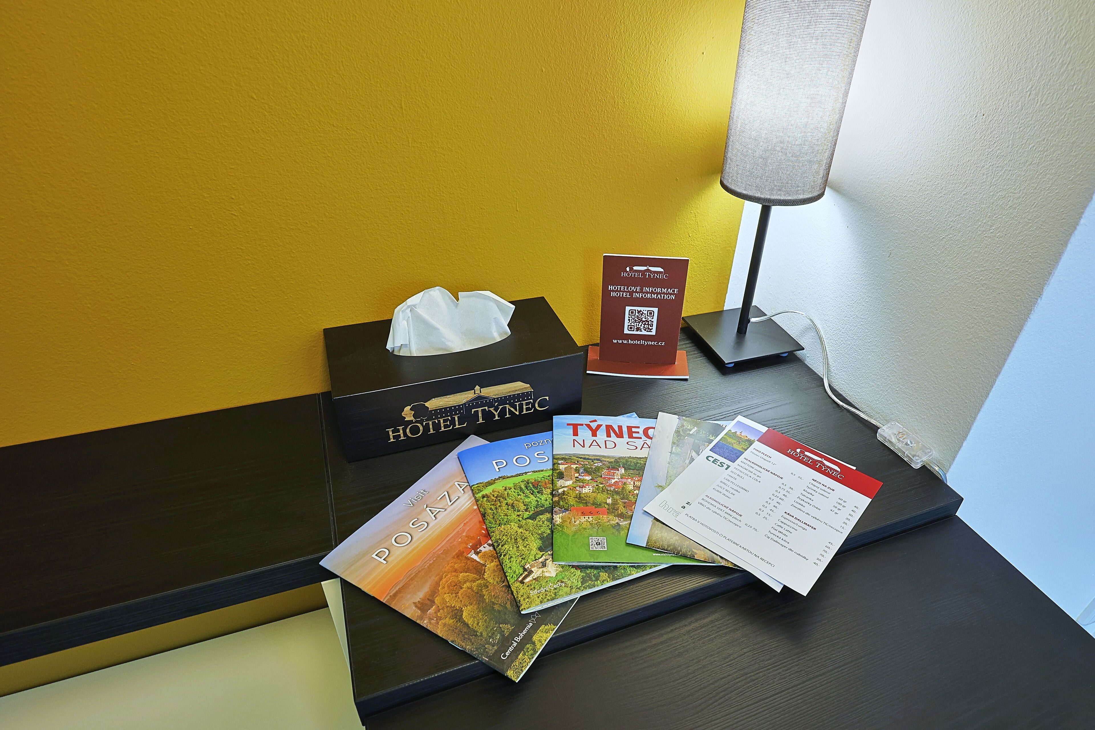 A hotel reception desk with a tissue box, a brochure stand, and a lamp.