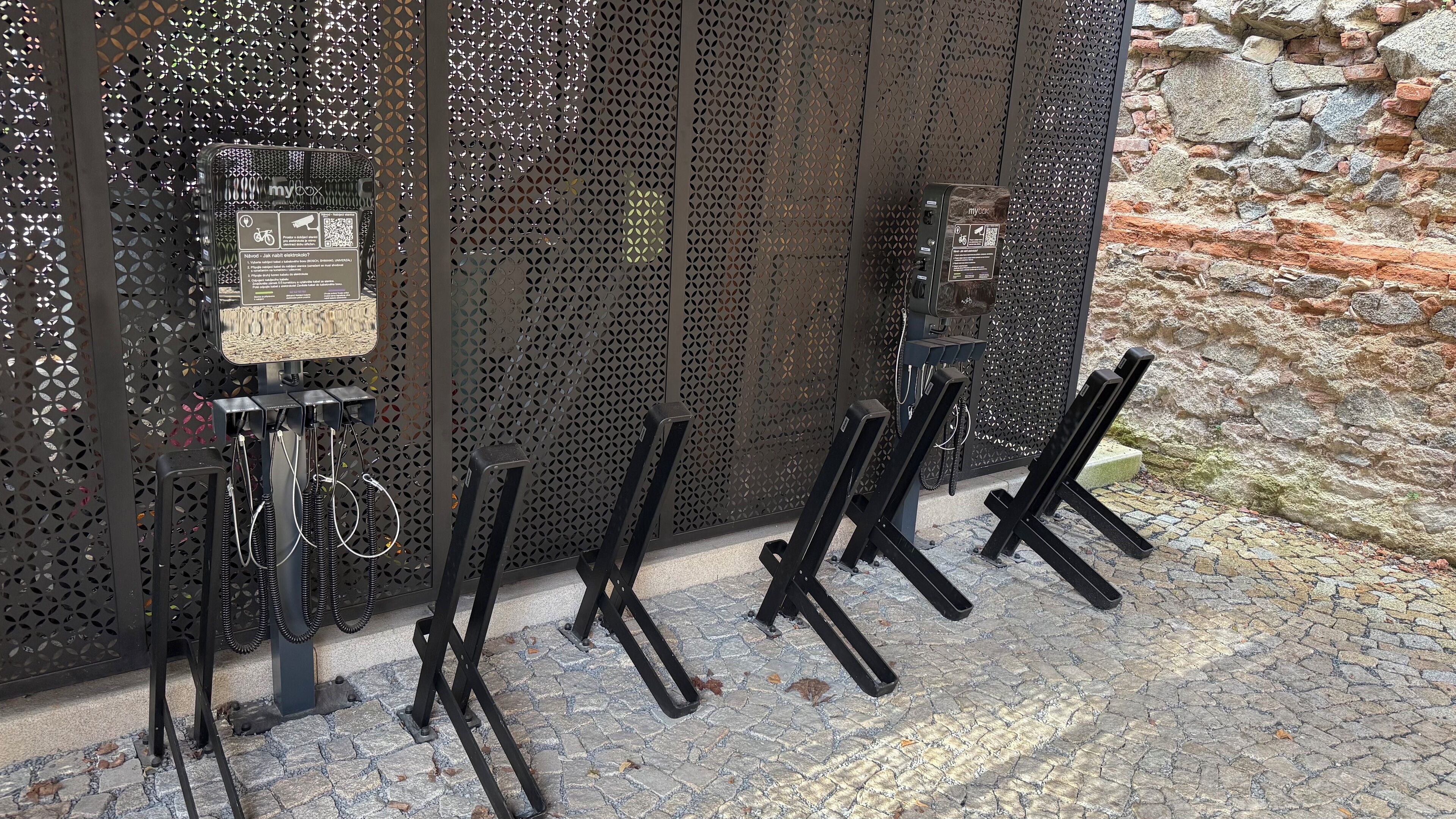 A security gate with a metal mesh design, two electronic devices, and a cobblestone ground.