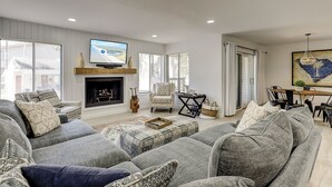A living room with a fireplace, a television, and a dining area with a table and chairs. - 2 bed/3 bath villa, spacious and updated townhouse with view of the pool (Hilton Head)