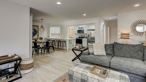 A modern living room with a grey sofa, a coffee table, and a dining area with a wooden table and chairs. - 2 bed/3 bath villa, spacious and updated townhouse with view of the pool (Hilton Head)