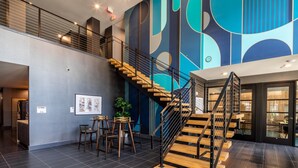 A modern interior with a staircase, a seating area, and a large abstract mural on the wall. - Hyatus Luxury Residences City Crossing (New Haven)