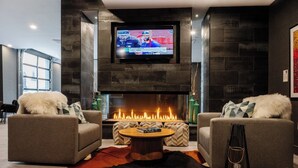A modern living room with a fireplace, two sofas, a coffee table, and a TV mounted on the wall. - Hyatus Luxury Residences City Crossing (New Haven)