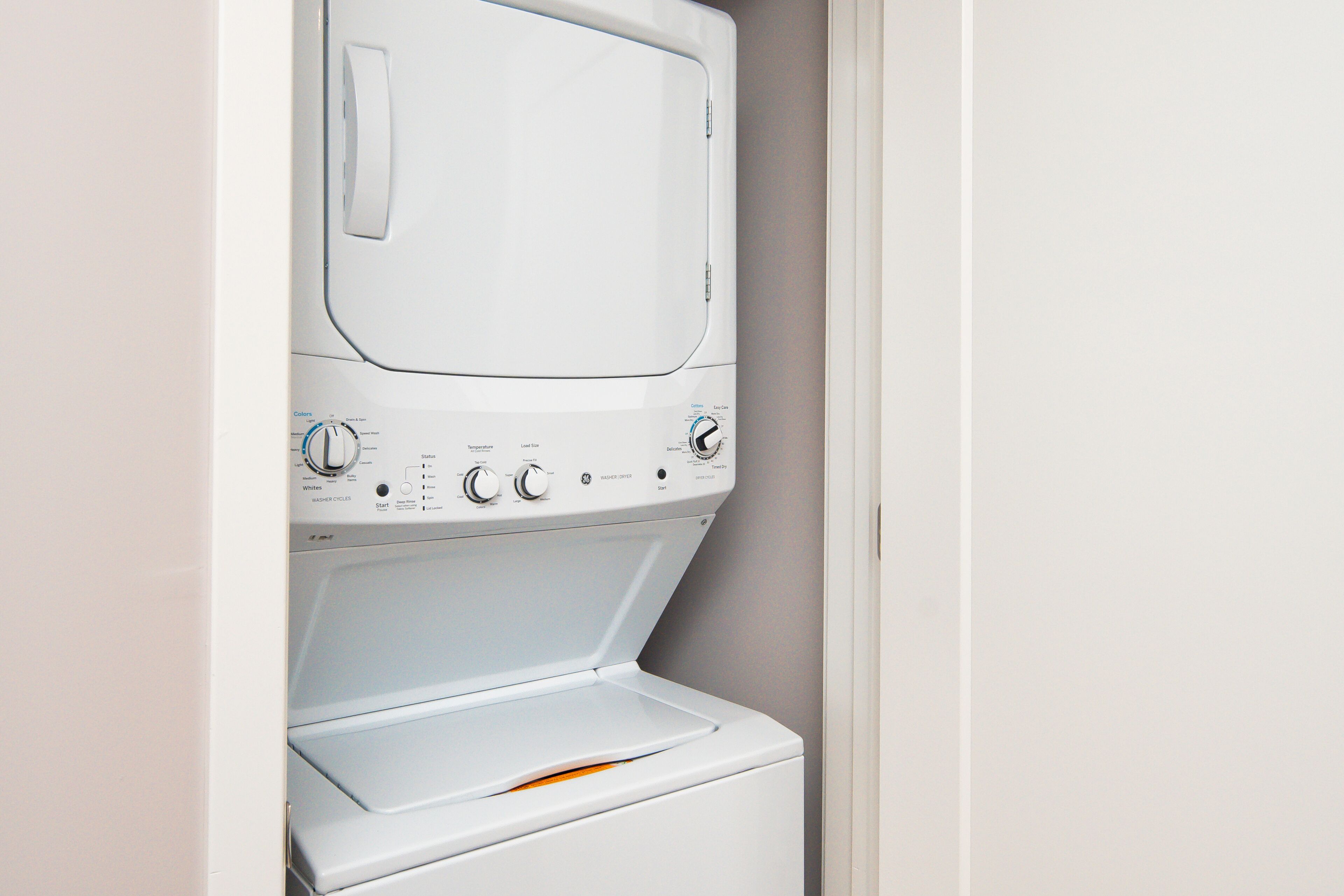 A front view of a white washing machine with control knobs and a detergent drawer.