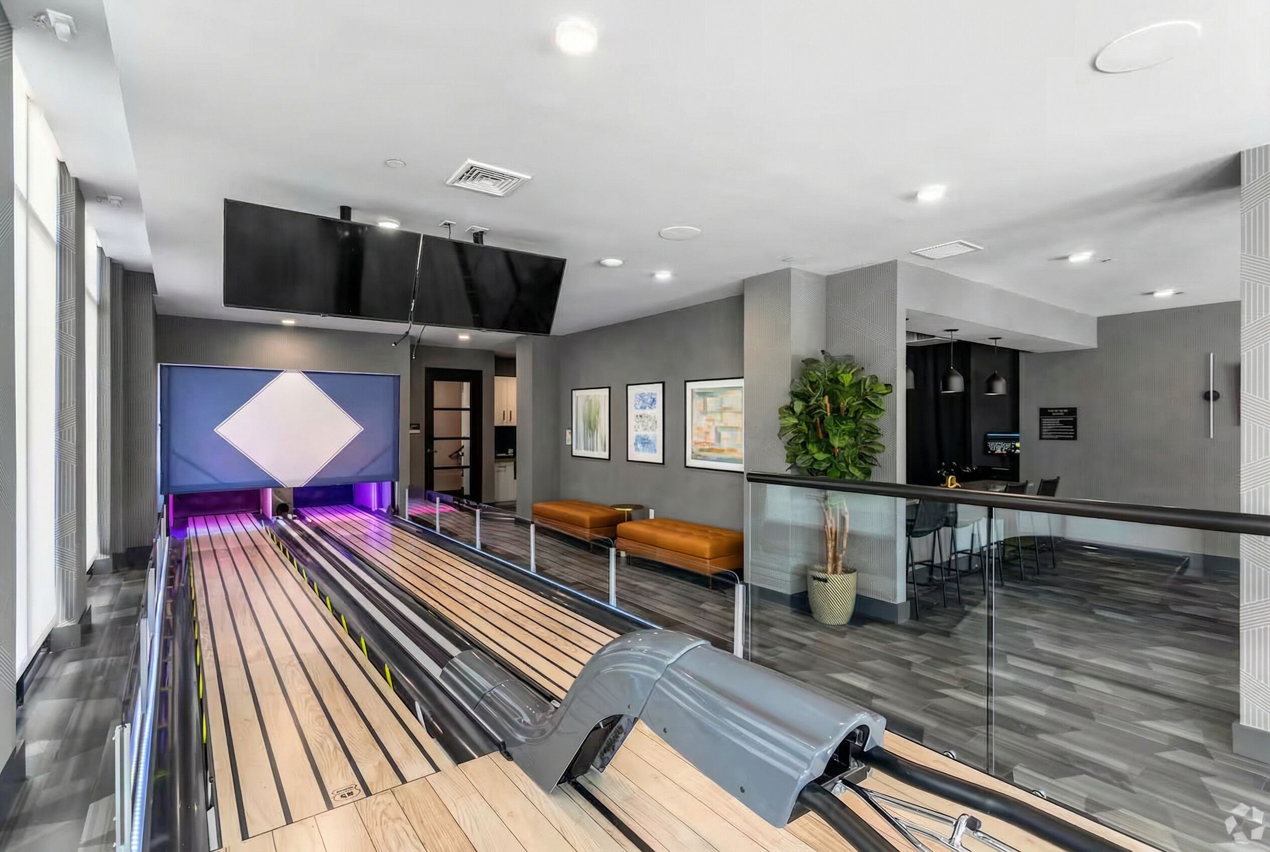 Un hall d’hôtel moderne avec un comptoir d’accueil, un espace salon et un grand écran.