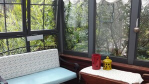 A conservatory with a blue patterned bench, a red stool, a wooden table with a white tablecloth, and a yellow decorative item. - Bassin d'Arcachon family home with swimming pool (LE TEICH)