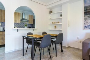A modern kitchen with wooden cabinets, a built-in stove, and a dining area with a table and chairs. - Apartment in Fuengirola near train station (Fuengirola)