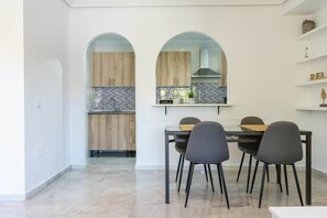 A modern kitchen with wooden cabinets, a tiled backsplash, and a dining area with a table and chairs. - Apartment in Fuengirola near train station (Fuengirola)