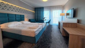 A hotel room with a large bed, a desk, a chair, and a TV.