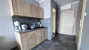 A compact kitchen with wooden cabinets, a countertop, and a coffee maker.