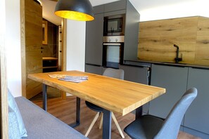 Una cocina compacta con una mesa de madera, sillas y un horno empotrado.