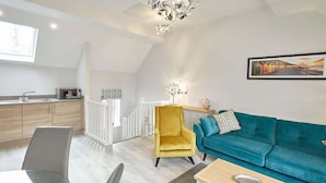 Una sala de estar moderna con un sofá color esmeralda, un sillón amarillo y una mesa de comedor de vidrio.