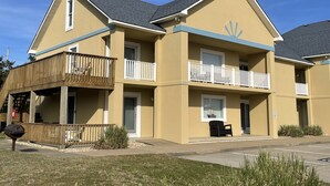 Un motel de dos pisos con fachada amarilla, balcones y el número de unidad 201 visible.