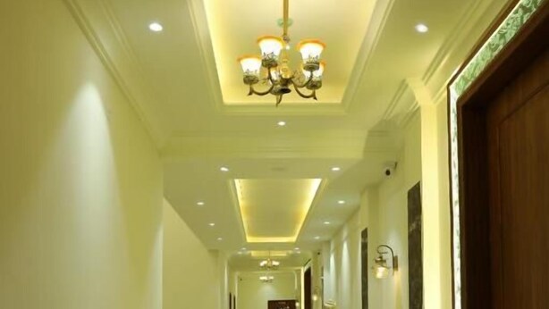 A long, well-lit hallway with a chandelier, polished floors, and wooden doors. - Ratna Vilas Palace (Rajkot)