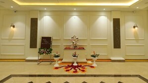 A reception area with a central statue, a welcome sign, and potted plants. - Ratna Vilas Palace (Rajkot)