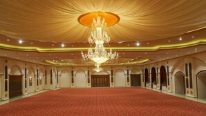 A large hall with a red carpet, a grand chandelier, and arched doorways. - Ratna Vilas Palace (Rajkot)