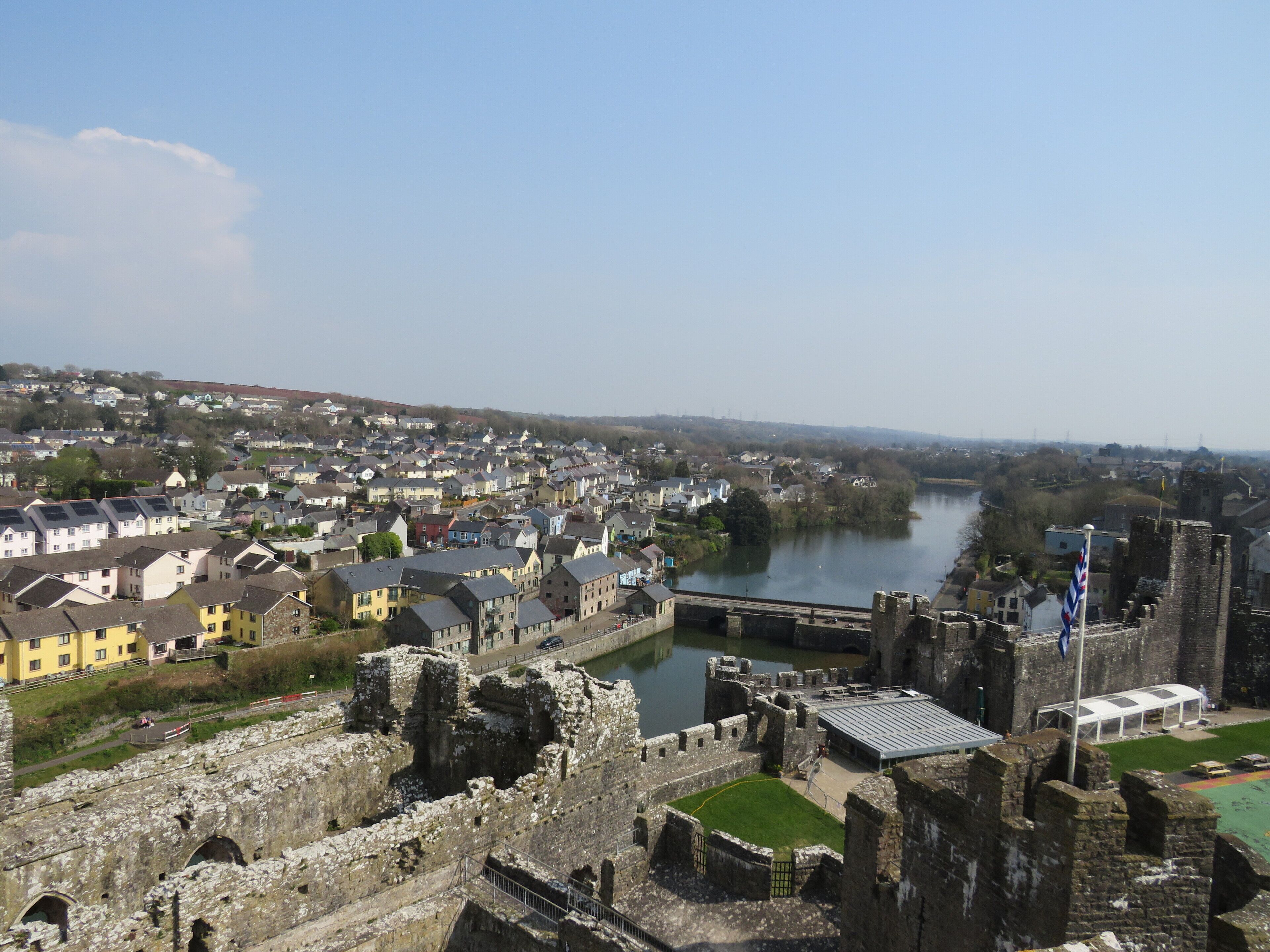 A historic castle with a moat, surrounded by residential buildings and a river.