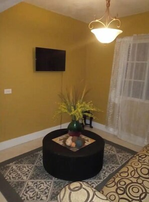 Relax in a stylish space with a vibrant accent wall, a geometric-patterned rug, and a modern pendant light.