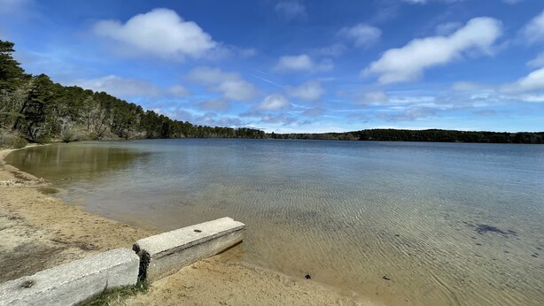 Un lago tranquilo con una playa de arena y una estructura de hormigón.