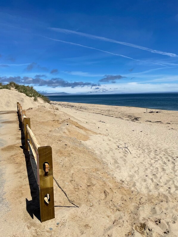 Una playa arenosa con barreras de madera y una vista despejada del océano.