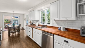Una cocina moderna con armarios blancos, encimeras de madera y lavavajillas integrado.