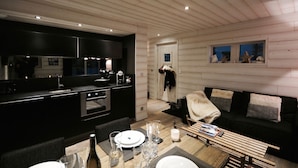 Una cocina moderna con armarios oscuros y un comedor con una mesa de madera para cuatro.