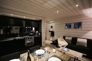 A modern kitchen with dark cabinetry and a dining area with a wooden table set for four. - Chalet Minkar Greniers d'Alpages (Bolquère)