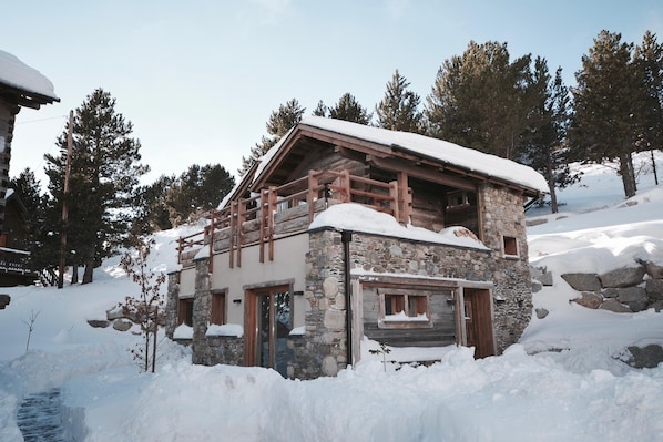 A stone cabin with a wooden balcony, surrounded by snow and trees. - Chalet Minkar Greniers d'Alpages (Bolquère)