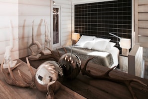 A modern bedroom with a large bed, a wooden floor, and a black tiled wall. - Chalet Minkar Greniers d'Alpages (Bolquère)
