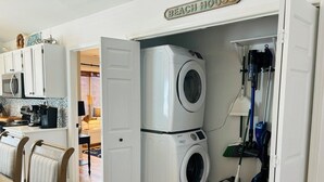 Un lavadero con lavadora y secadora, un comedor con mesa y sillas, y una cocina con armarios y electrodomésticos.