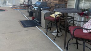 Eine Terrasse im Freien mit Grill, Sitzgelegenheiten und einem Pool.