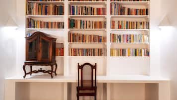 A room with a white bookshelf filled with books, a wooden chair, and a wooden cabinet.