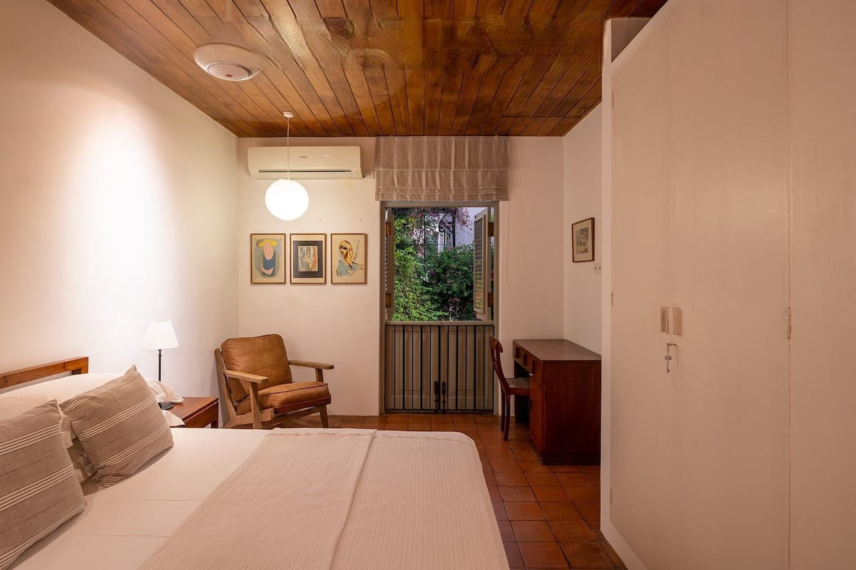 Une chambre à coucher comprenant un lit, une chaise, un bureau et une fenêtre donnant sur un paysage verdoyant.