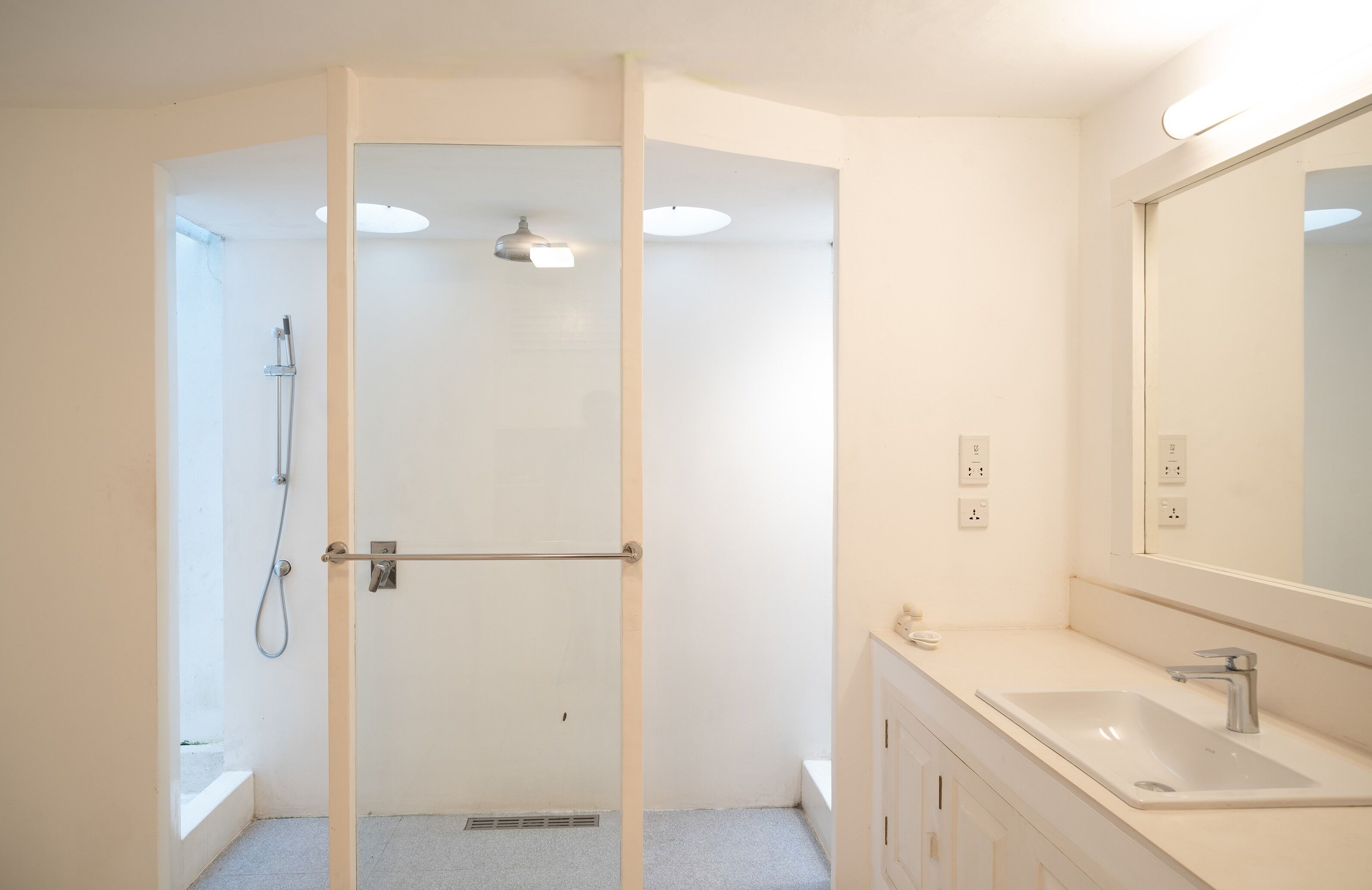 Un bagno moderno con doccia vetrata, lavabo e specchio grande.