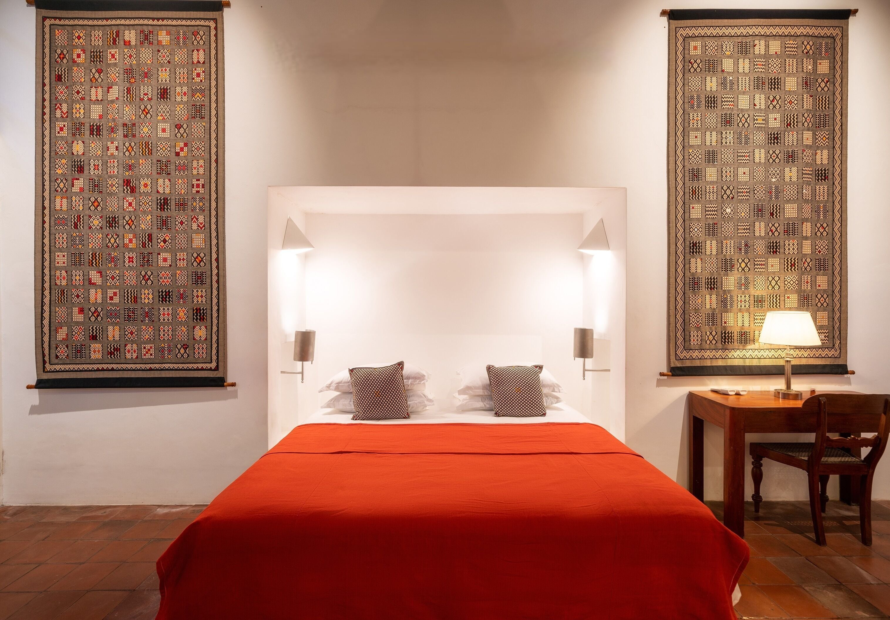 Una habitación de hotel con una cama grande, dos lámparas de noche, un escritorio con silla y dos paneles decorativos en la pared.