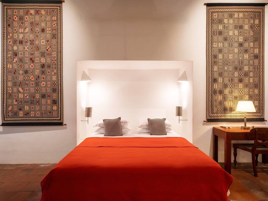 Una habitación de hotel con una cama grande, dos lámparas de noche, un escritorio con silla y dos paneles decorativos en la pared.