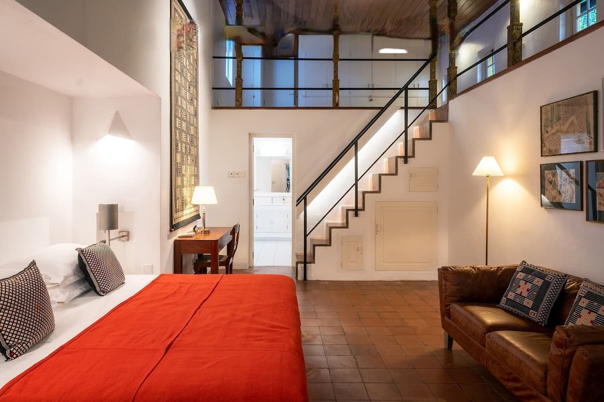 Une chambre d’hôtel avec un lit, un canapé, un escalier et un bureau.