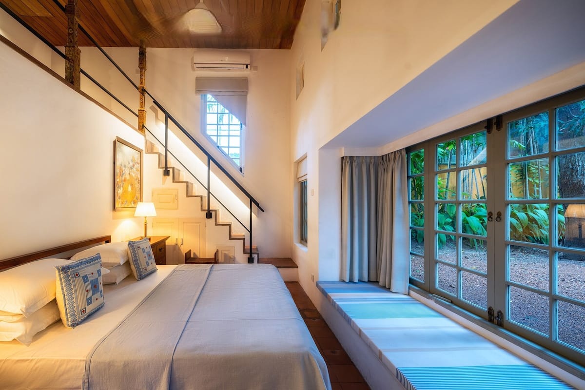 Une chambre à coucher avec un lit, un escalier et une grande fenêtre donnant sur un paysage verdoyant.