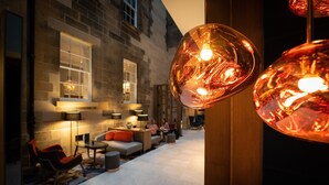 A modern lobby with stone walls, a seating area with sofas and chairs, and pendant lighting.
