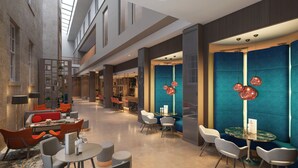 A spacious lobby with high ceilings, modern seating, and a central bar area.